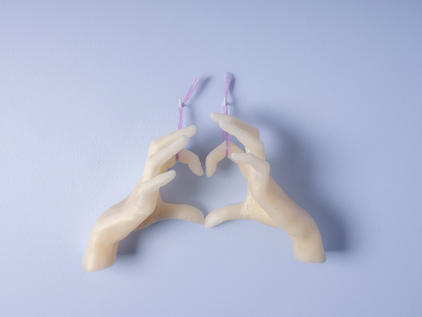 Focus sur moulages de mains en cire formant un cœur. Extrait de l'installation Spring Spleen.