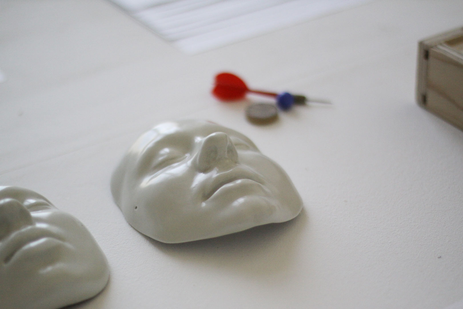 Détails sur les masque en porcelaines présenté dans l'installation intitulée "Mouvement perpétuel". Les masque sont en porcelaine émaillée, brillante, blanchâtre.