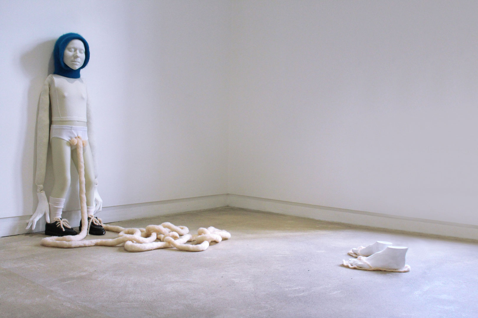 Vues de l'installation intitulée "Douces indolences" montrant à gauche un personnage longeant un mur et à droite une paire de pieds sans corps.