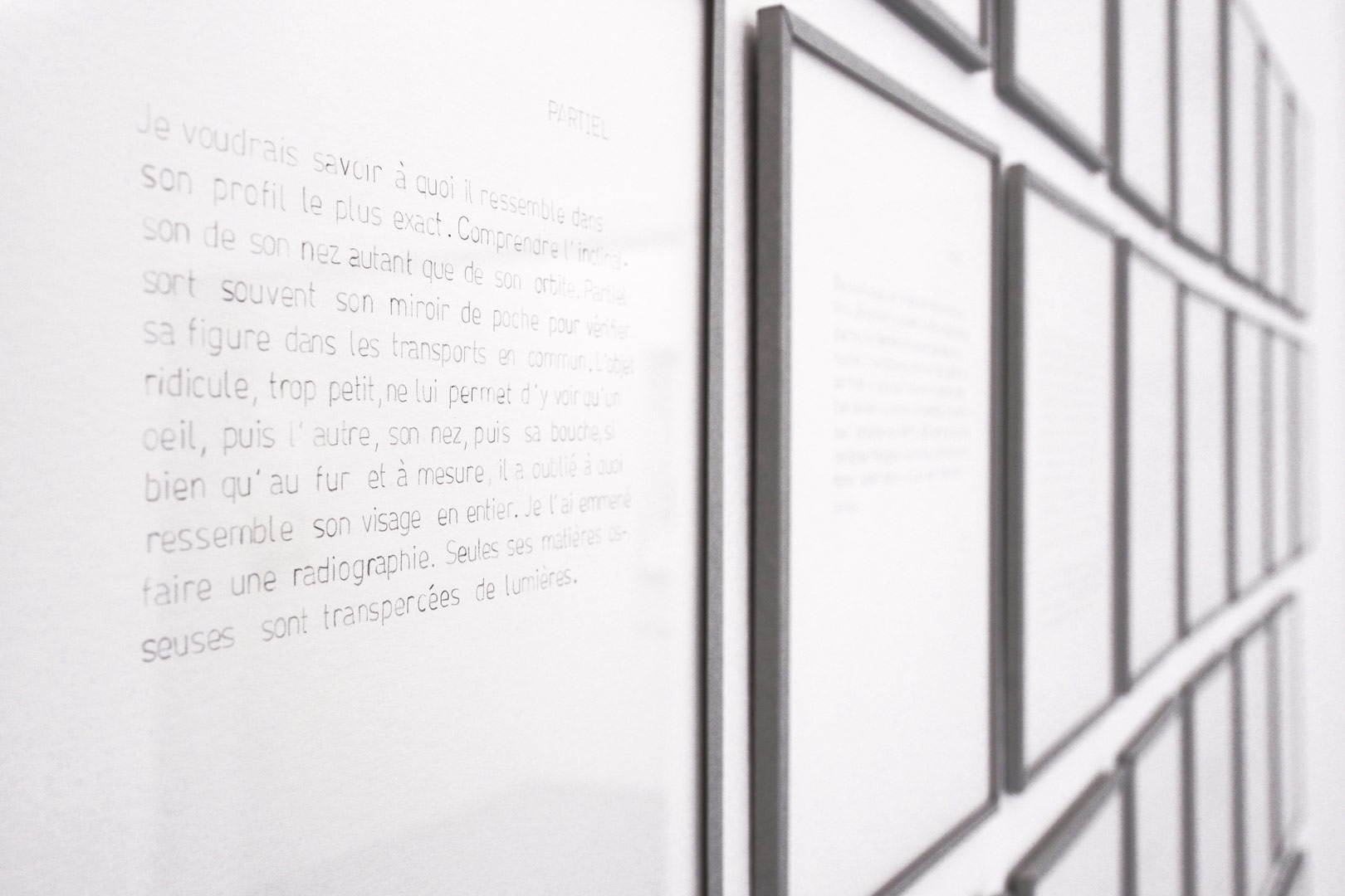 Focus resserré de l'installation intitulée "Soliloques" détaillant les 40 textes tracés au graphite à l'aide d'un normographe. Les textes sont encadrés et bordés du même papier bleu pale que les boites présentent dans l'installation.
